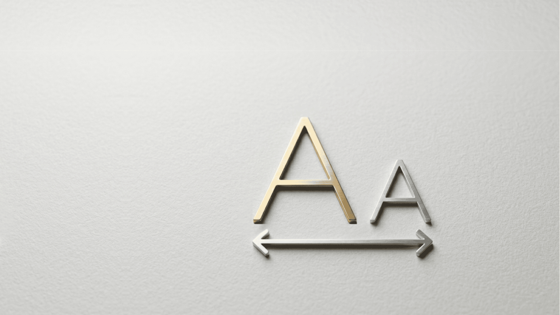 A minimalist and elegant close-up of two stylized, metallic 'A' characters—one gold and one silver—resting on a high-quality, textured white paper surface. A sleek silver double-headed arrow lies beneath them, symbolizing the fluid scalability and adaptive display of the interface. The clean composition and soft lighting reflect THE WISHLINE's commitment to inclusive luxury and accessible design
