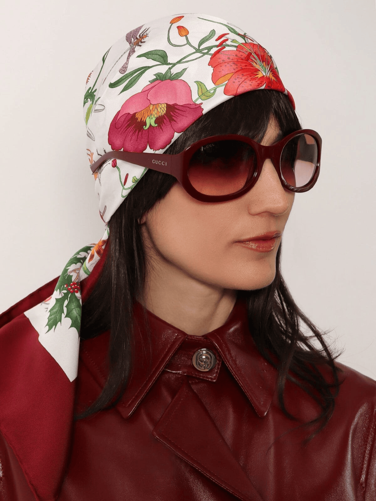 Model in Gucci sunglasses and printed silk headscarf with red leather coat – Gucci Women's Collection.