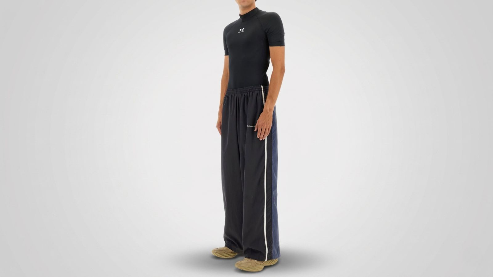 Black tight-fit compression t-shirt, paired with navy blue loose-fit track pants with side stripes and tan athletic sneakers for THE WISHLINE luxury men's activewear and designer sportswear collection navigation.