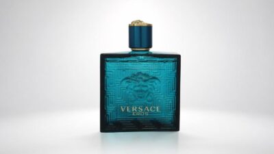 Versace Eros aftershave lotion bottle featuring its iconic turquoise blue glass design with the raised Medusa head motif and Greek key border for THE WISHLINE luxury men's after shave and grooming collection navigation.