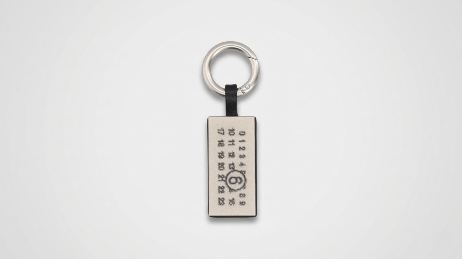 MM6 Maison Margiela silver-tone rectangular metal keychain featuring the signature engraved numeric logo grid with a circled number 6 for THE WISHLINE luxury men's assorted accessories and keyrings collection navigation.