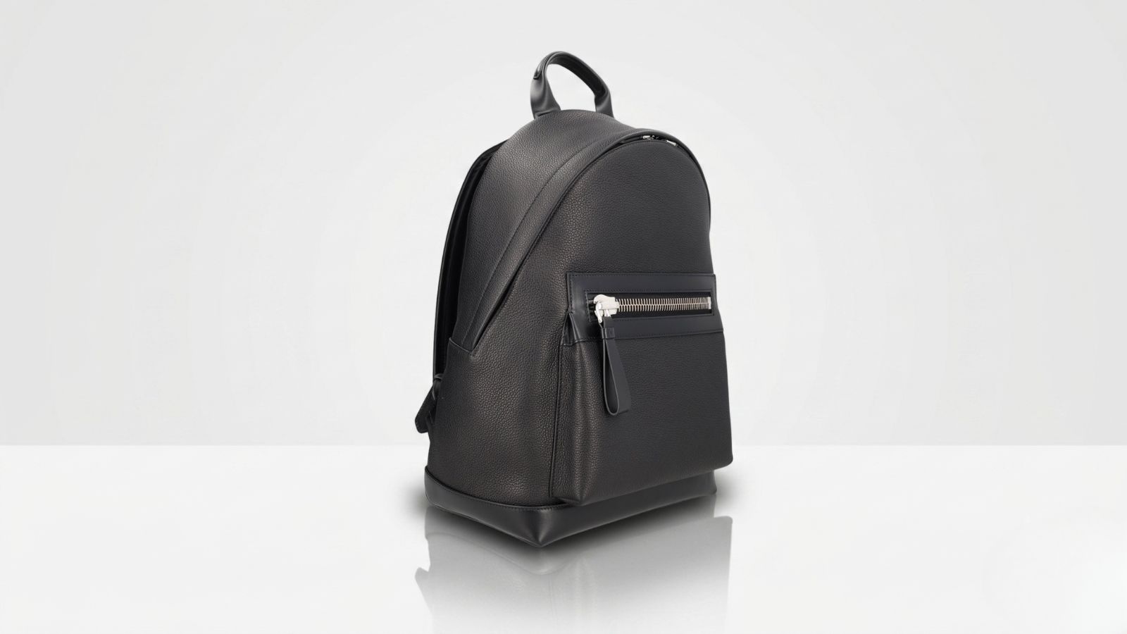 Tom Ford black pebbled leather backpack featuring a structured minimalist design with a silver-tone chunky zipper front pocket for THE WISHLINE luxury men's backpacks collection navigation.