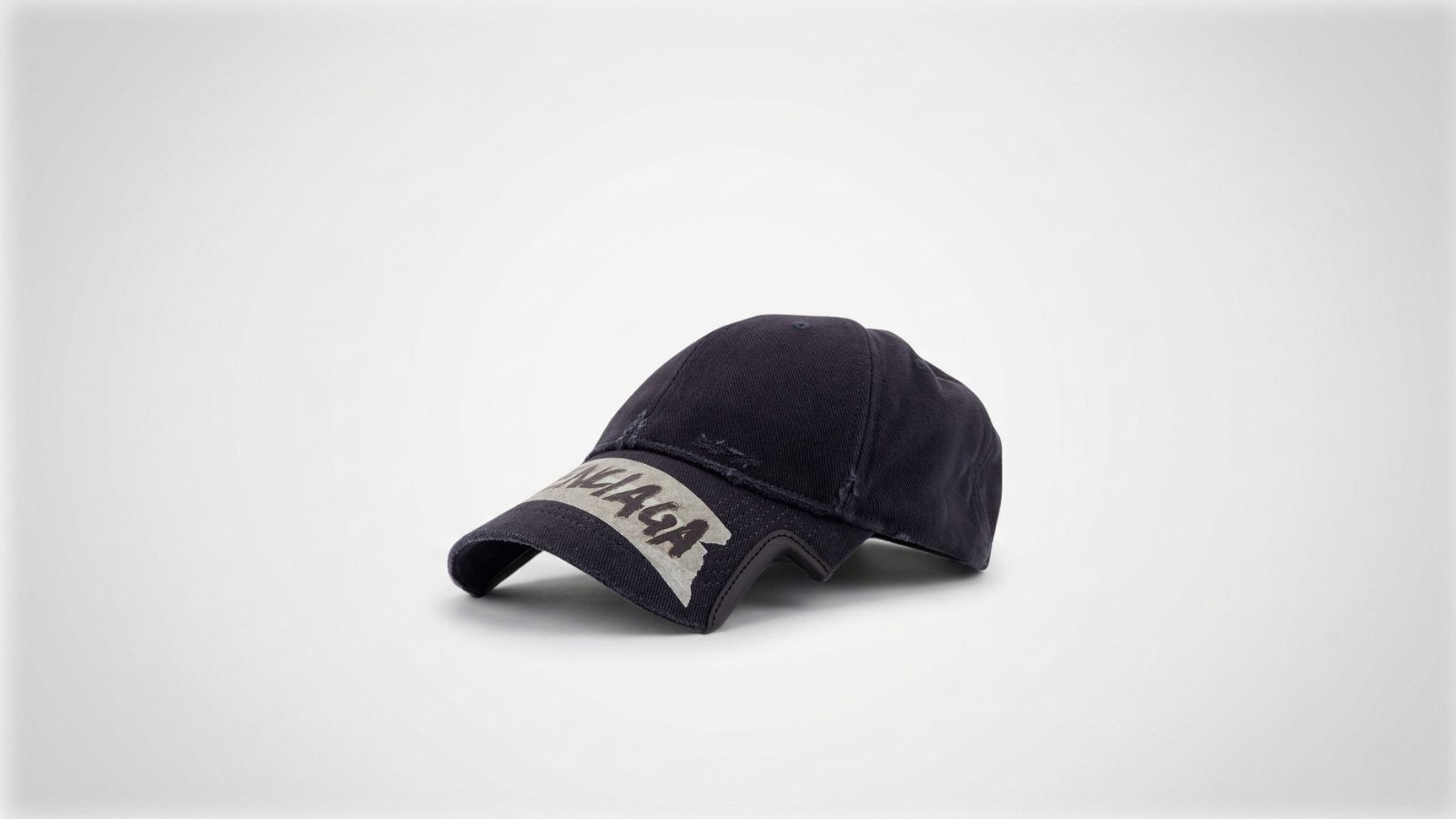 Balenciaga washed black distressed cotton baseball cap featuring a tape-effect logo graphic on a notched brim for THE WISHLINE luxury men's caps and hats collection navigation.