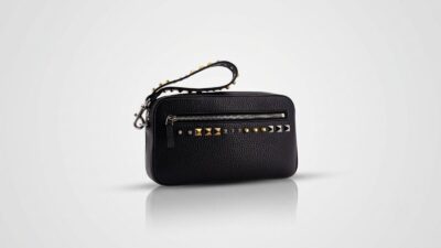 Valentino Garavani black leather pouch featuring a zip-top closure and a structured wristlet strap for THE WISHLINE luxury men's clutches and pouches collection navigation.