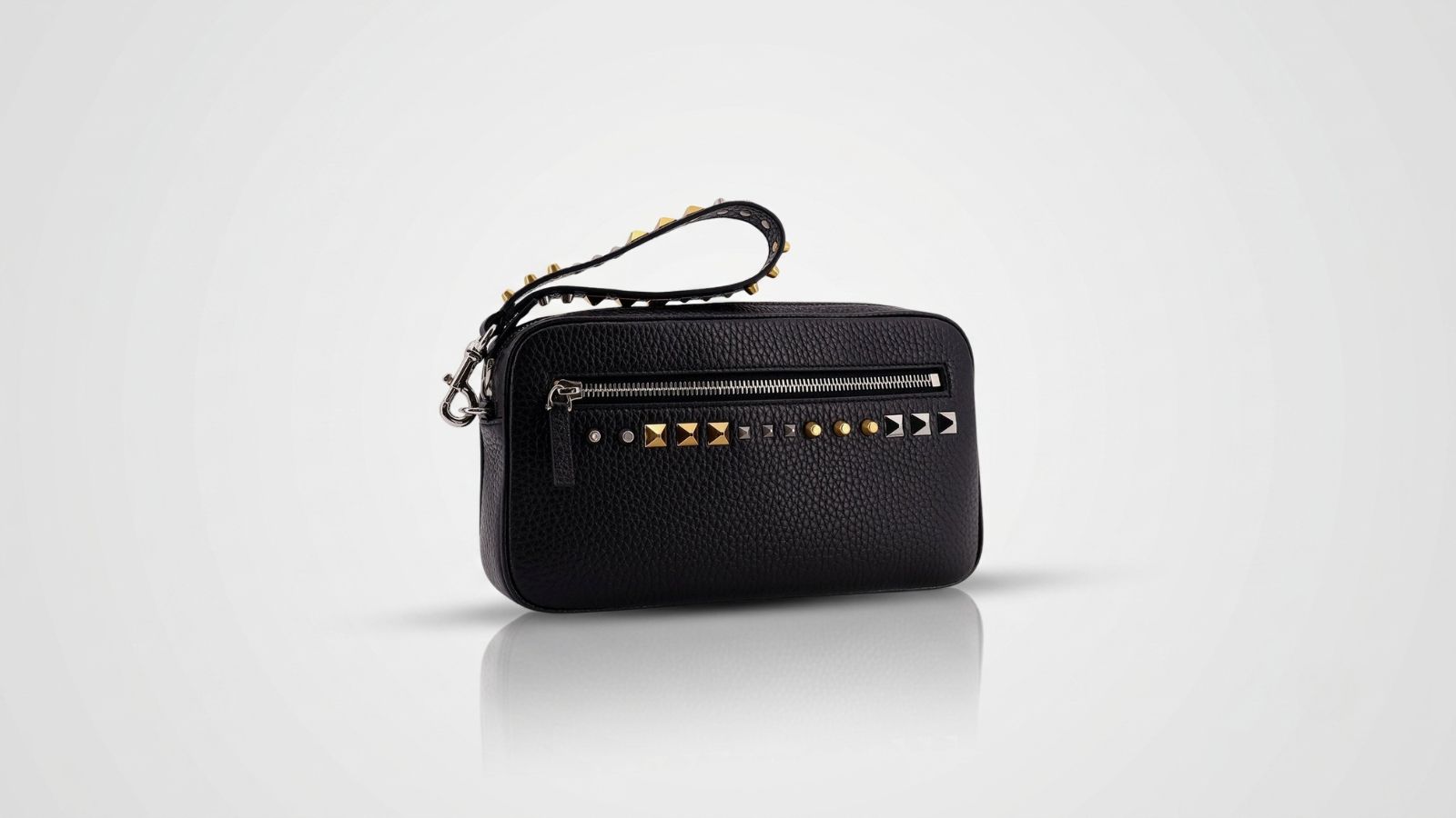 Valentino Garavani black leather pouch featuring a zip-top closure and a structured wristlet strap for THE WISHLINE luxury men's clutches and pouches collection navigation.