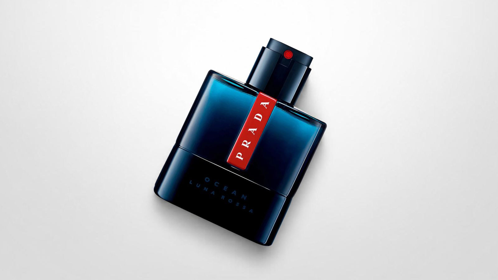 Prada Luna Rossa Ocean Eau de Toilette bottle featuring a deep blue translucent glass design with the iconic red stripe logo insert for THE WISHLINE luxury men's eau de toilette and cologne collection navigation.