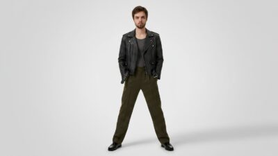 Classic black leather biker jacket with silver hardware, layered over a grey ribbed top and paired with olive green pleated trousers and black leather loafers for THE WISHLINE luxury men's jackets and coats collection navigation.