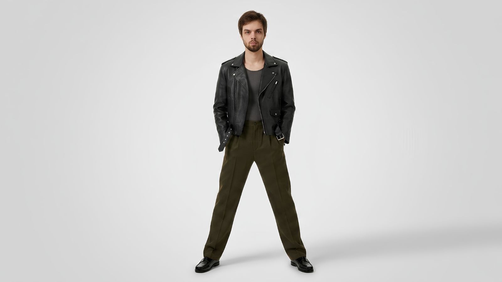 Classic black leather biker jacket with silver hardware, layered over a grey ribbed top and paired with olive green pleated trousers and black leather loafers for THE WISHLINE luxury men's jackets and coats collection navigation.