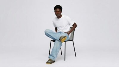 Light wash wide-leg denim jeans paired with a classic white crewneck T-shirt and olive green sneakers for THE WISHLINE luxury men's jeans and trousers collection navigation