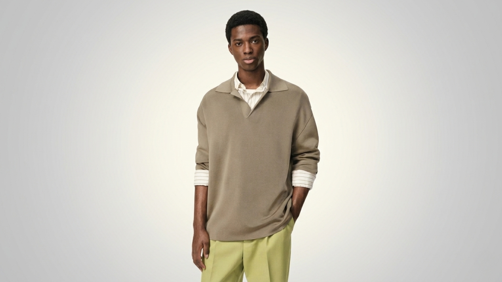 Taupe brown oversized knit polo shirt layered over a striped button-up shirt and paired with lime green trousers for THE WISHLINE luxury men's polo shirts collection navigation.