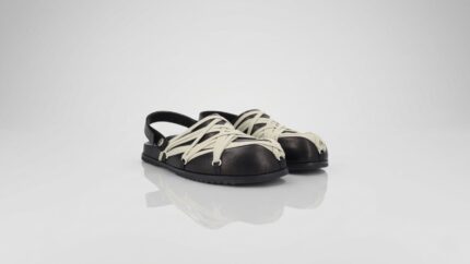 Black leather slingback sandals featuring an intricate off-white lace-up cage design over a rounded toe for THE WISHLINE luxury men's sandals and flats collection navigation.