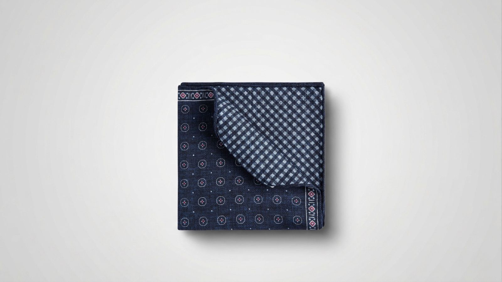 Brunello Cucinelli navy blue silk-blend pocket square featuring a dual-sided design with geometric medallions and a gingham check pattern for THE WISHLINE luxury men's scarves and pocket squares collection navigation.