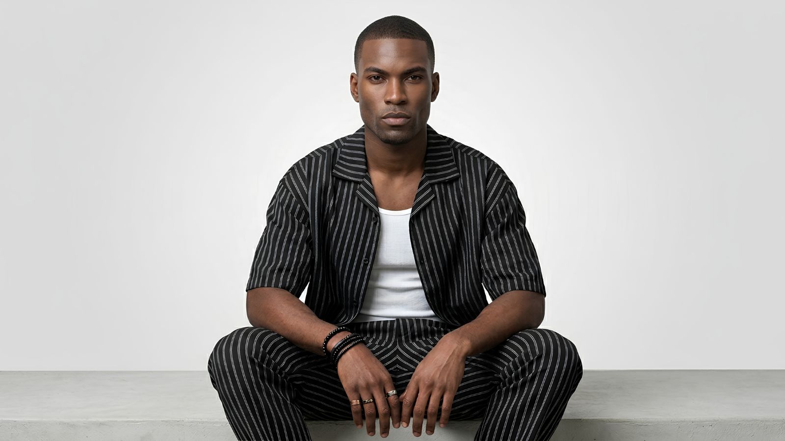 Black and white pinstripe short-sleeve camp collar shirt layered over a ribbed white tank top for THE WISHLINE luxury men's shirts and casual button-ups collection navigation.