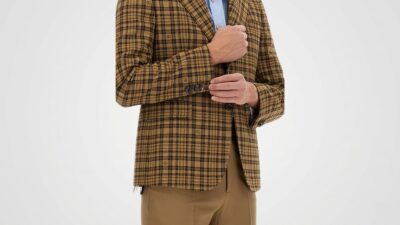 Tan and brown plaid check blazer layered over a light blue button-up shirt and paired with camel brown dress trousers for THE WISHLINE luxury men's suits and blazers collection navigation.