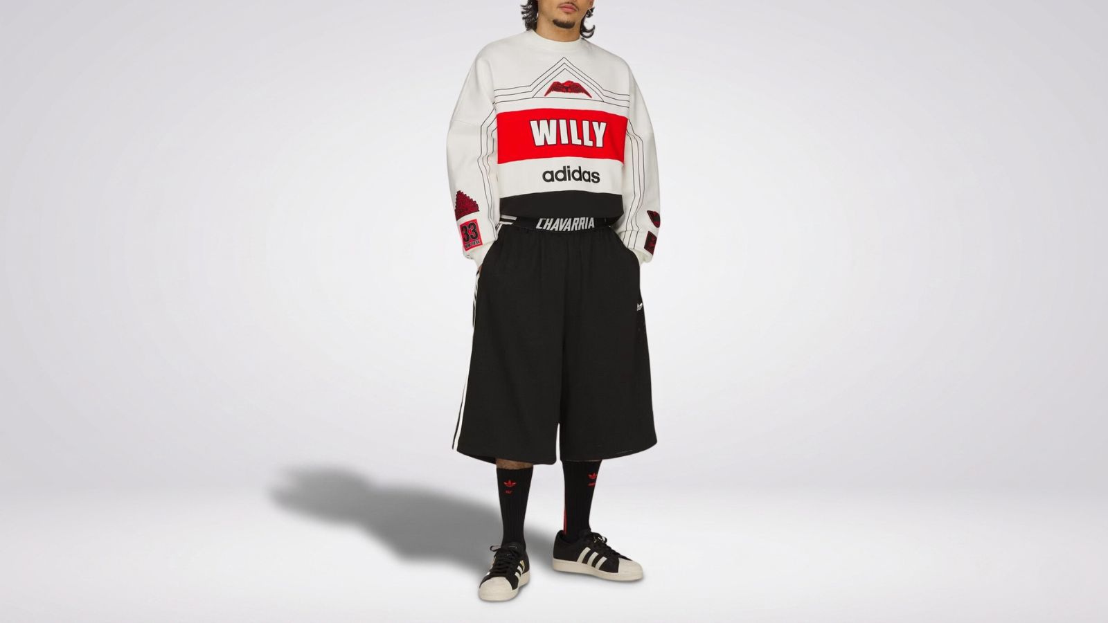 Willy Chavarria x Adidas oversized colorblock sweatshirt featuring bold graphic logos paired with black wide-leg shorts and sneakers for THE WISHLINE luxury men's sweatshirts and hoodies collection navigation.