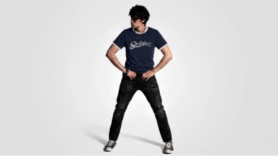 Navy blue distressed ringer T-shirt featuring a white cursive logo graphic paired with black ripped jeans for THE WISHLINE luxury men's T-shirts and streetwear collection navigation.