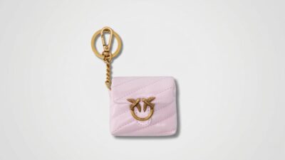 Light pink quilted leather tech case featuring a gold-tone metal bird buckle, attached to a matching gold keychain ring and lobster clasp for THE WISHLINE luxury women's assorted accessories, hair accessories, and lifestyle collection navigation.