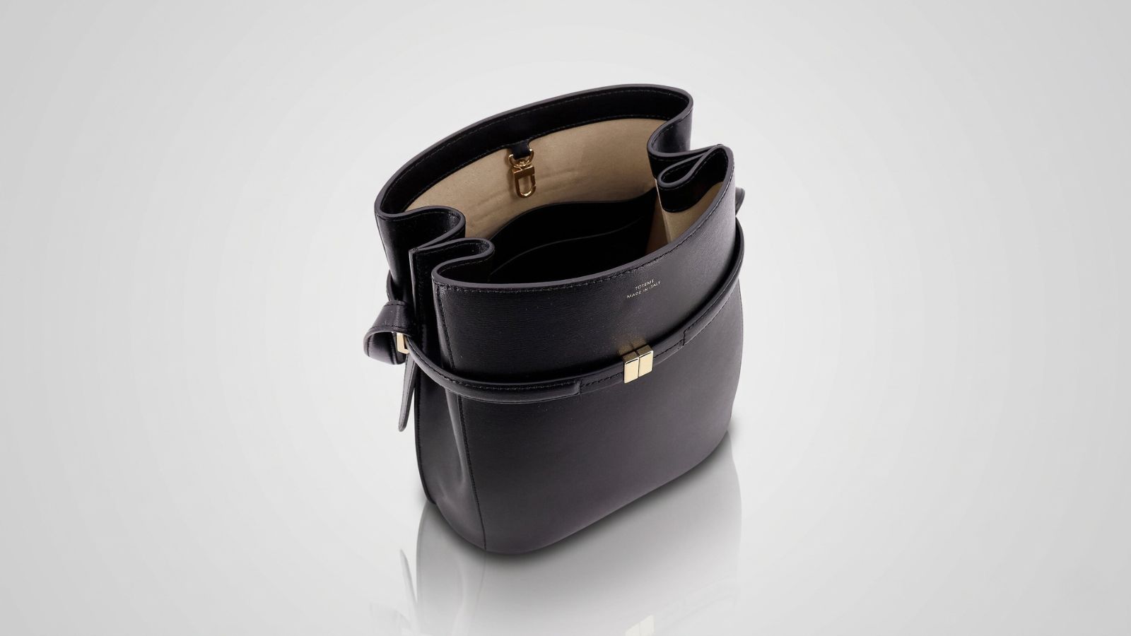 Toteme black leather bucket bag featuring a structured design with gold hardware accents and a spacious interior for THE WISHLINE designer women's assorted bags navigation.