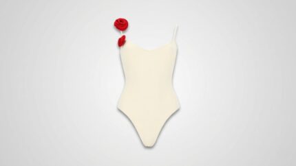 Elegant off-white one-piece swimsuit featuring a sweetheart neckline, thin spaghetti straps, and two vibrant red 3D rosette floral accents on the right shoulder for THE WISHLINE luxury women's beachwear and designer swimwear collection navigation.