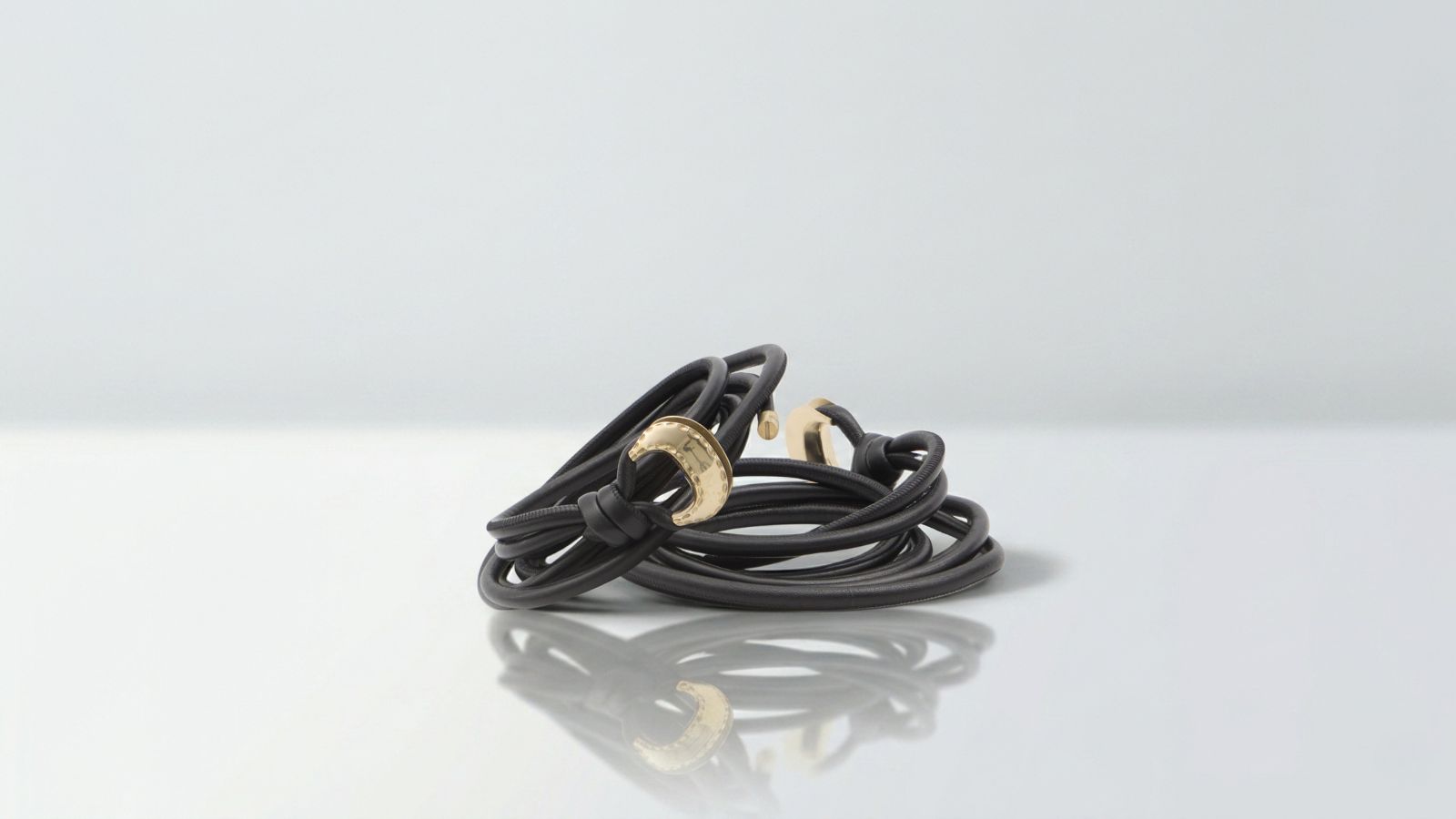 Luxury multi-wrap black leather cord belt featuring polished gold crescent buckle hardware for THE WISHLINE designer women's belts collection navigation.
