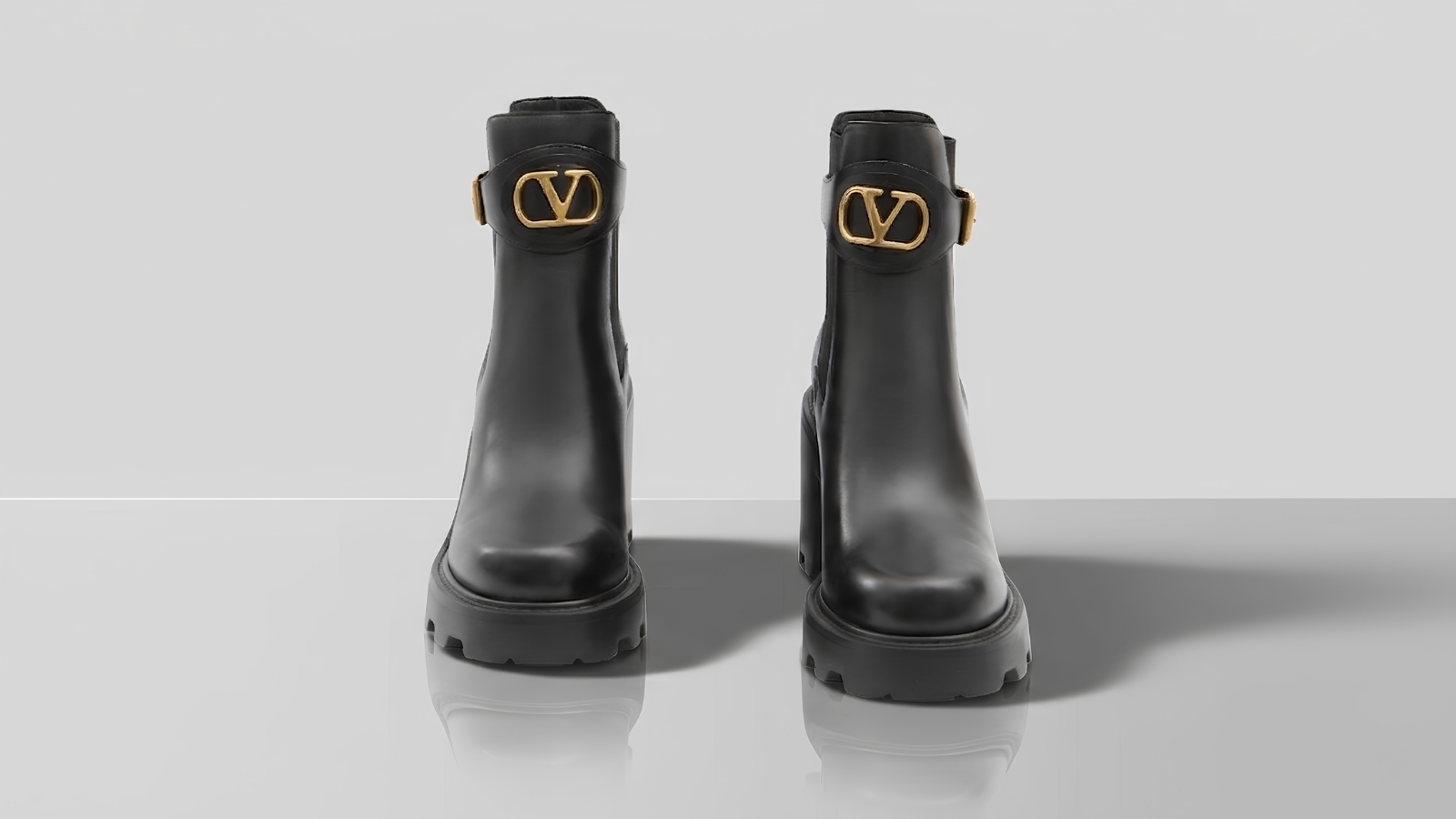 Valentino Garavani black leather ankle boots with gold VLogo buckle details and chunky lug soles for THE WISHLINE luxury women's boots collection navigation.