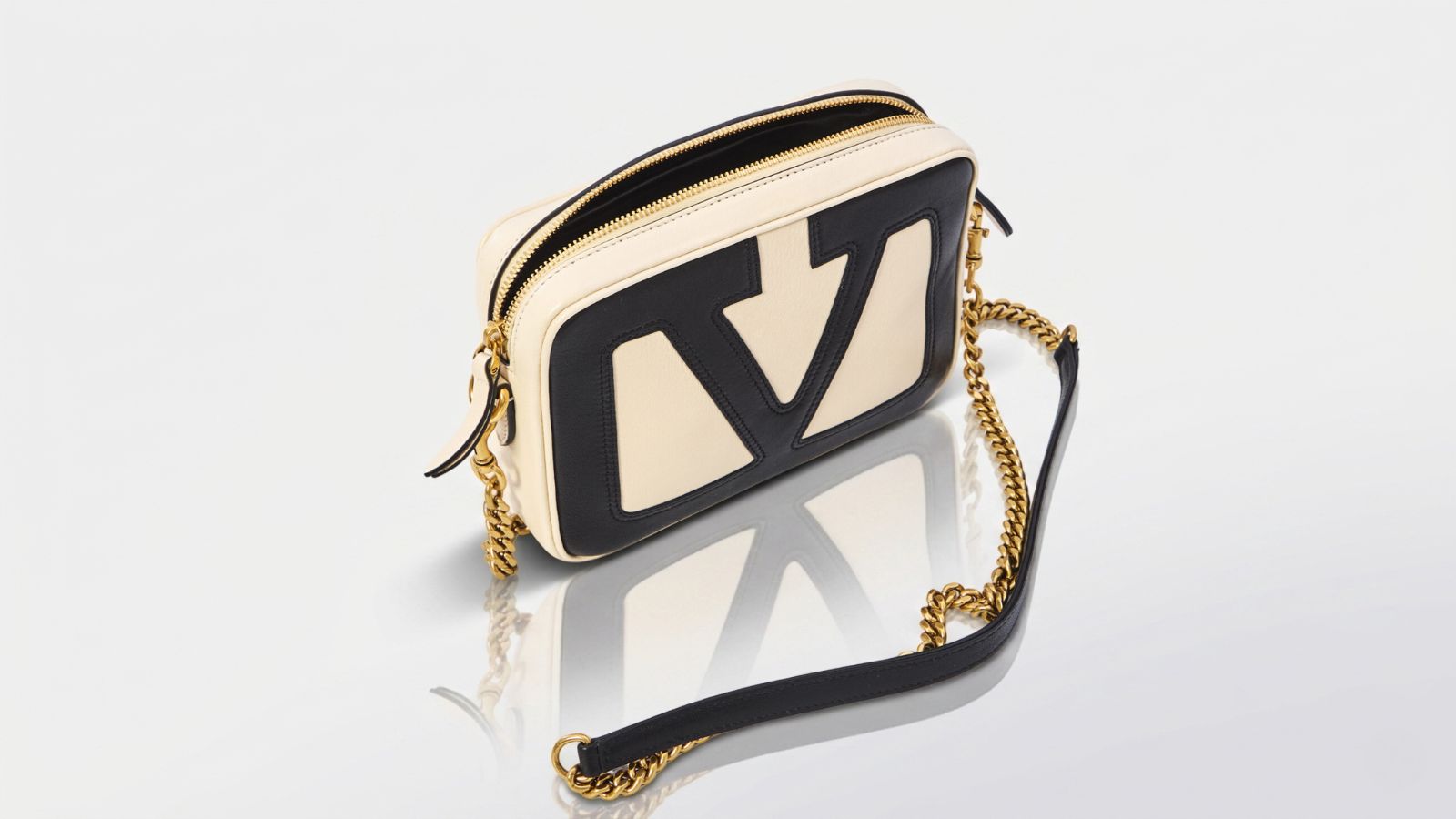 Valentino Garavani cream and black leather Locò camera bag featuring a prominent cut-out VLogo design and a gold-tone chain shoulder strap for THE WISHLINE luxury crossbody and shoulder bags navigation.