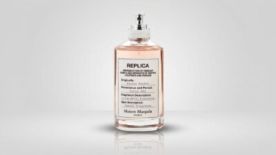 Clear glass apothecary-style perfume bottle filled with light pink liquid, featuring a white textured fabric label and a silver spray pump wrapped with white cord for THE WISHLINE luxury women's eau de toilette and premium fragrance collection navigation.