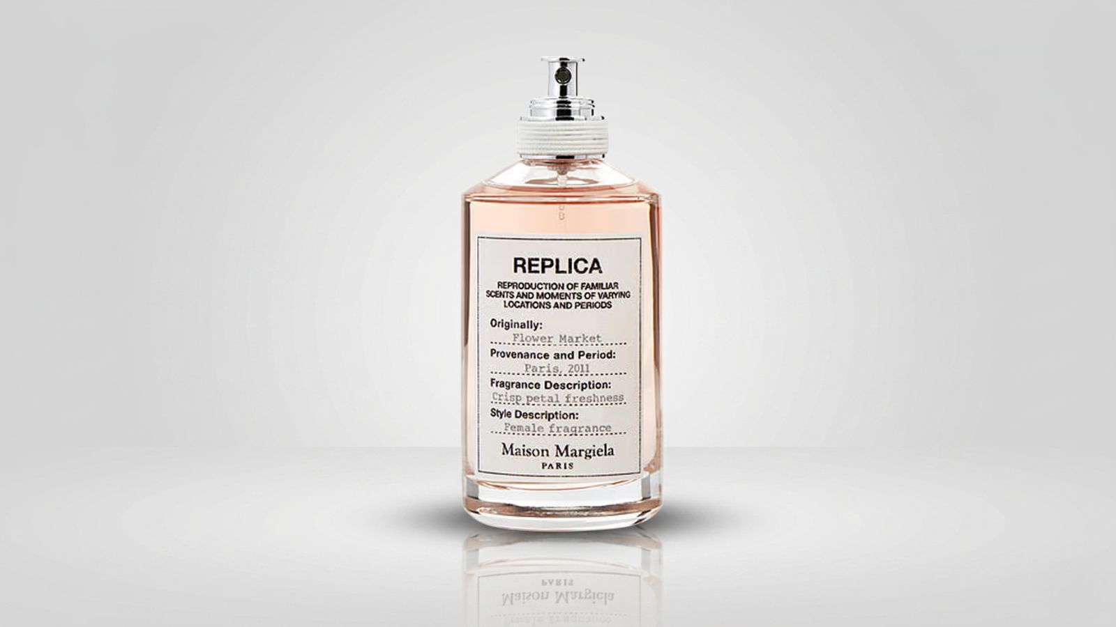 Clear glass apothecary-style perfume bottle filled with light pink liquid, featuring a white textured fabric label and a silver spray pump wrapped with white cord for THE WISHLINE luxury women's eau de toilette and premium fragrance collection navigation.