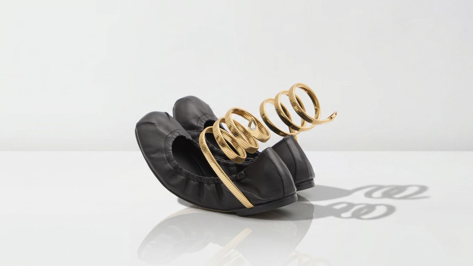 Luxury black leather ballerina flats featuring an iconic gold coil snake ankle wrap detail for THE WISHLINE designer flats and ballerinas navigation.
