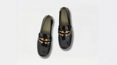 Bottega Veneta black patent leather loafers featuring prominent gold bit hardware details for THE WISHLINE luxury women's loafers collection navigation.