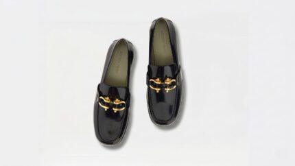Bottega Veneta black patent leather loafers featuring prominent gold bit hardware details for THE WISHLINE luxury women's loafers collection navigation.