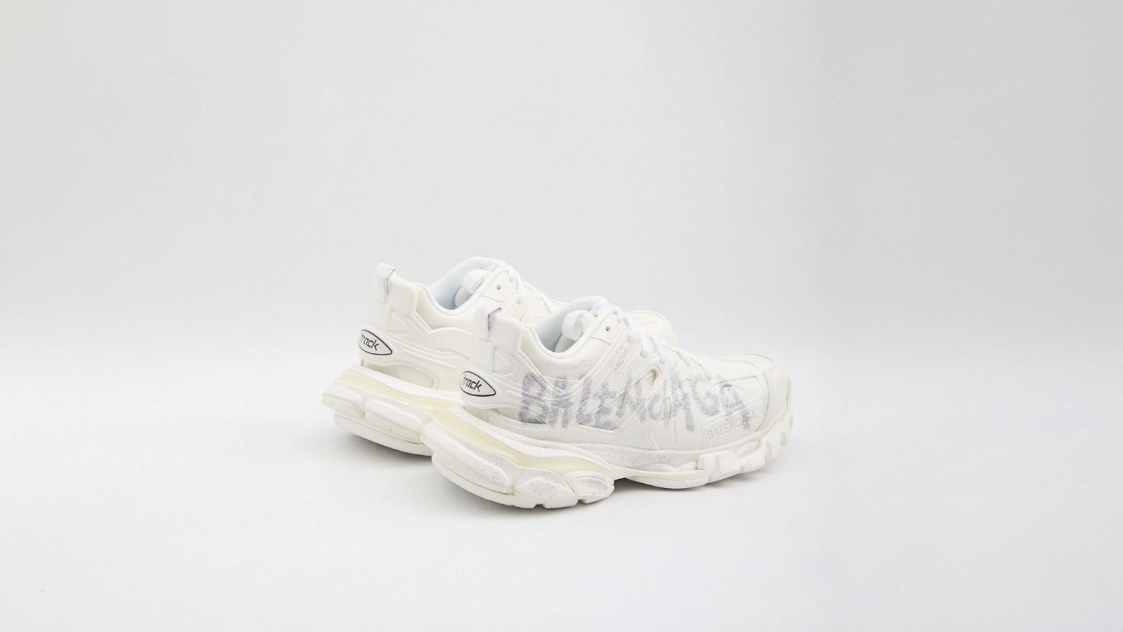 Balenciaga white Track sneakers featuring a distressed finish and hand-drawn style graffiti logo details for THE WISHLINE luxury women's sneakers collection navigation.