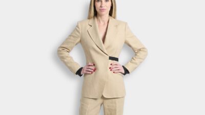 Model wearing a tailored tan linen blazer jacket with a black buckle waist detail for THE WISHLINE designer suits and blazers navigation.
