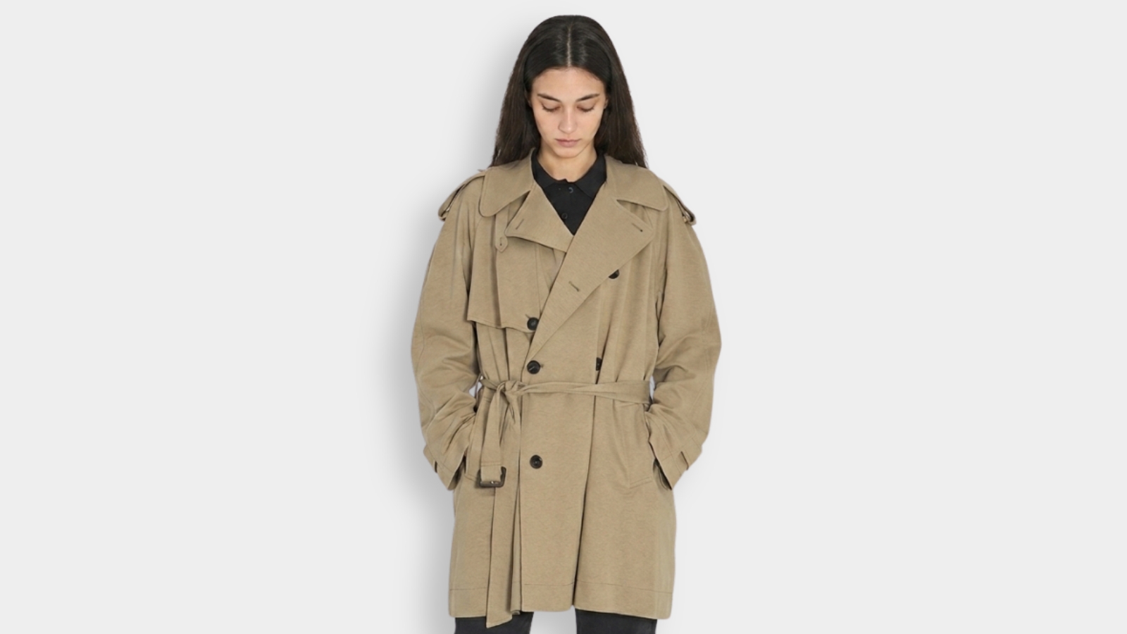 Model wearing a classic double-breasted tan trench coat with a waist belt and storm flaps for THE WISHLINE luxury women's trench coats collection navigation.