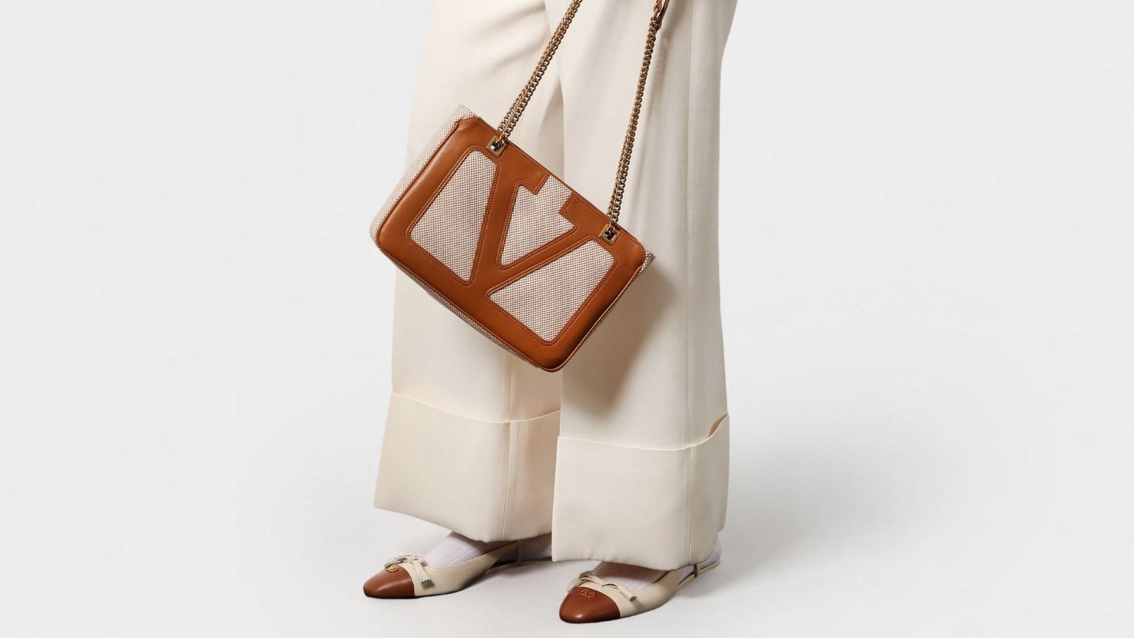 Valentino Garavani tan leather and canvas logo shoulder bag close-up for THE WISHLINE designer handbags collection navigation.