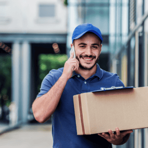 Smiling delivery person holding a package and talking on the phone.