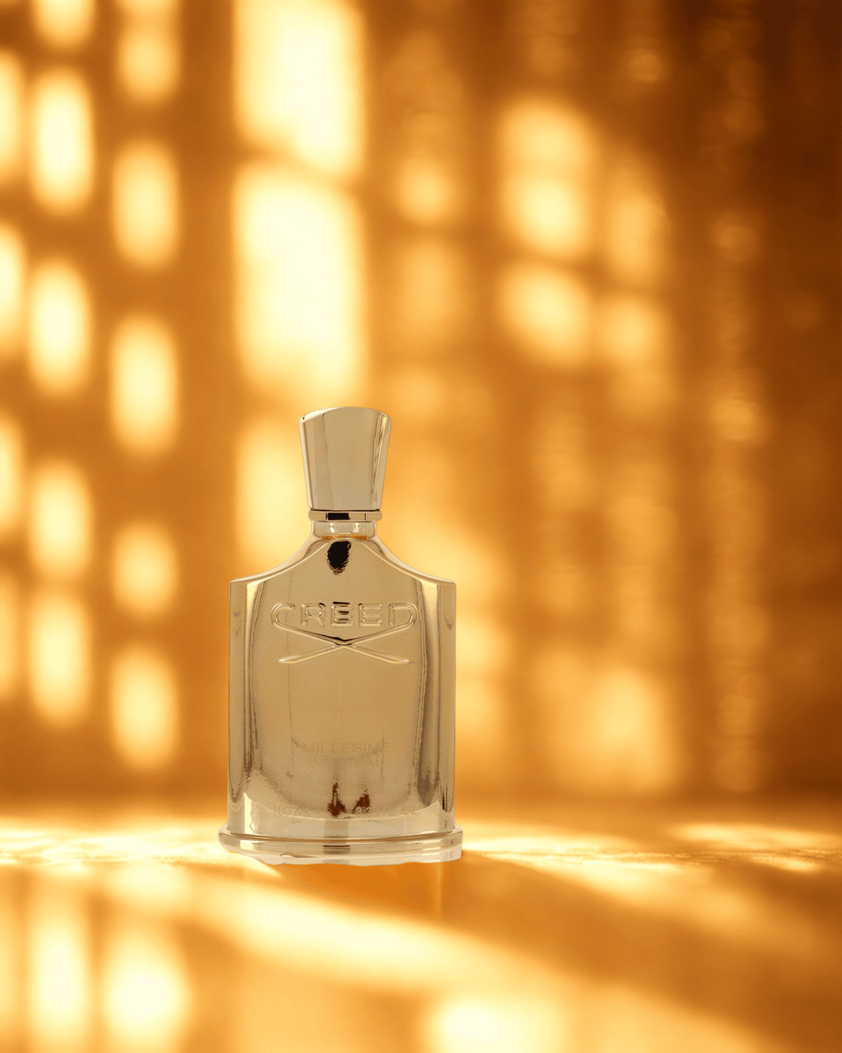 Creed Millesime Imperial gold perfume bottle illuminated by warm golden sunlight, symbolizing opulence and timeless sophistication.