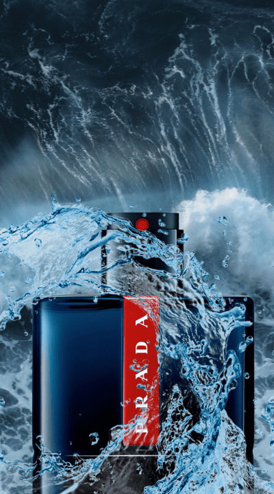 A deep blue luxury perfume bottle with a bold red stripe, surrounded by dynamic ocean waves and splashing water, evoking freshness and intensity.