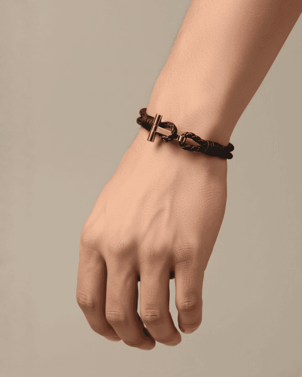 Close-up of a man’s wrist wearing a black braided leather bracelet with a gold T-bar clasp — featured in THE WISHLINE Men’s Jewellery Seasonal Offers collection.