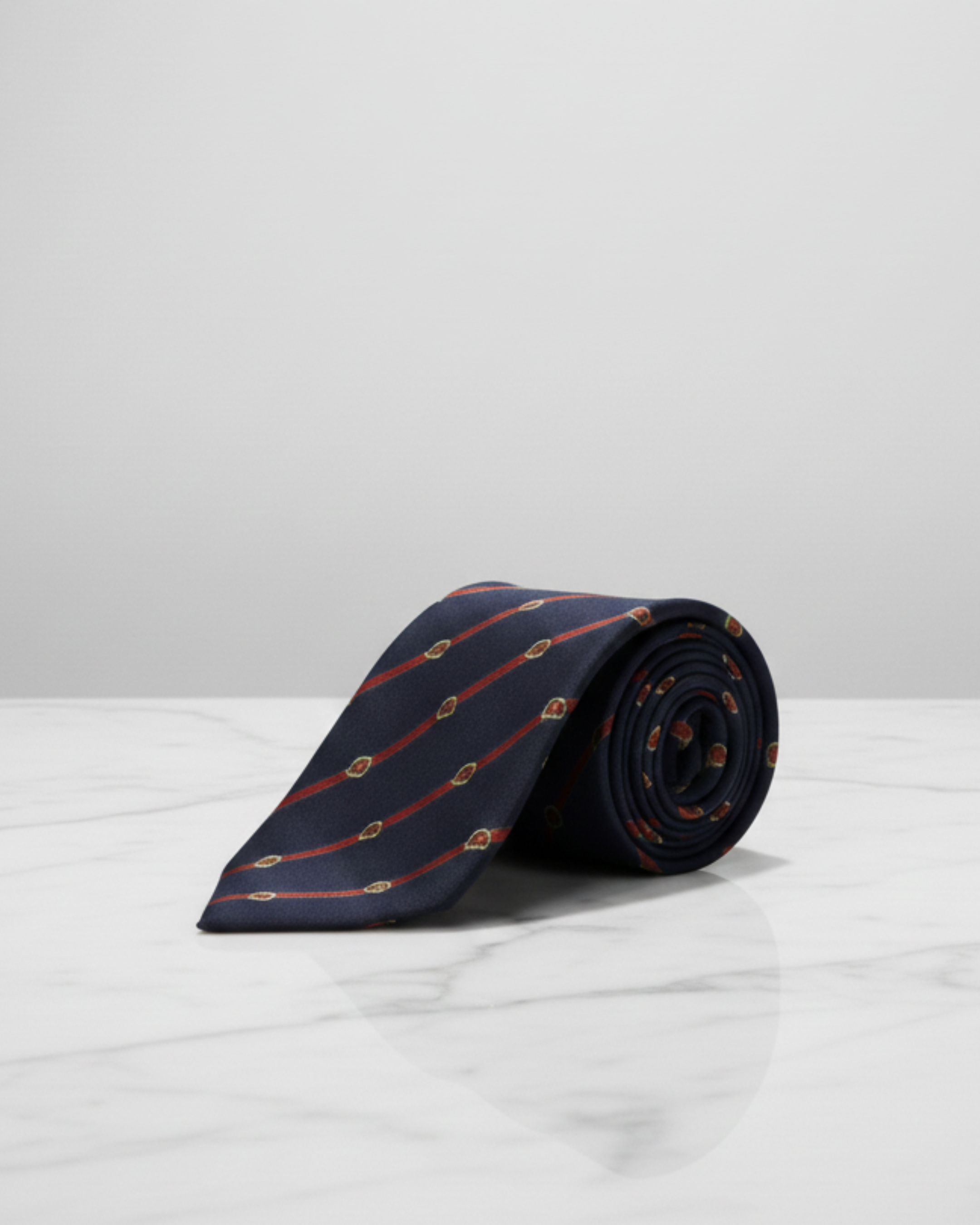 Navy blue silk tie with red diagonal stripes and small crest motifs, featured in THE WISHLINE Men’s Seasonal Offers collection.