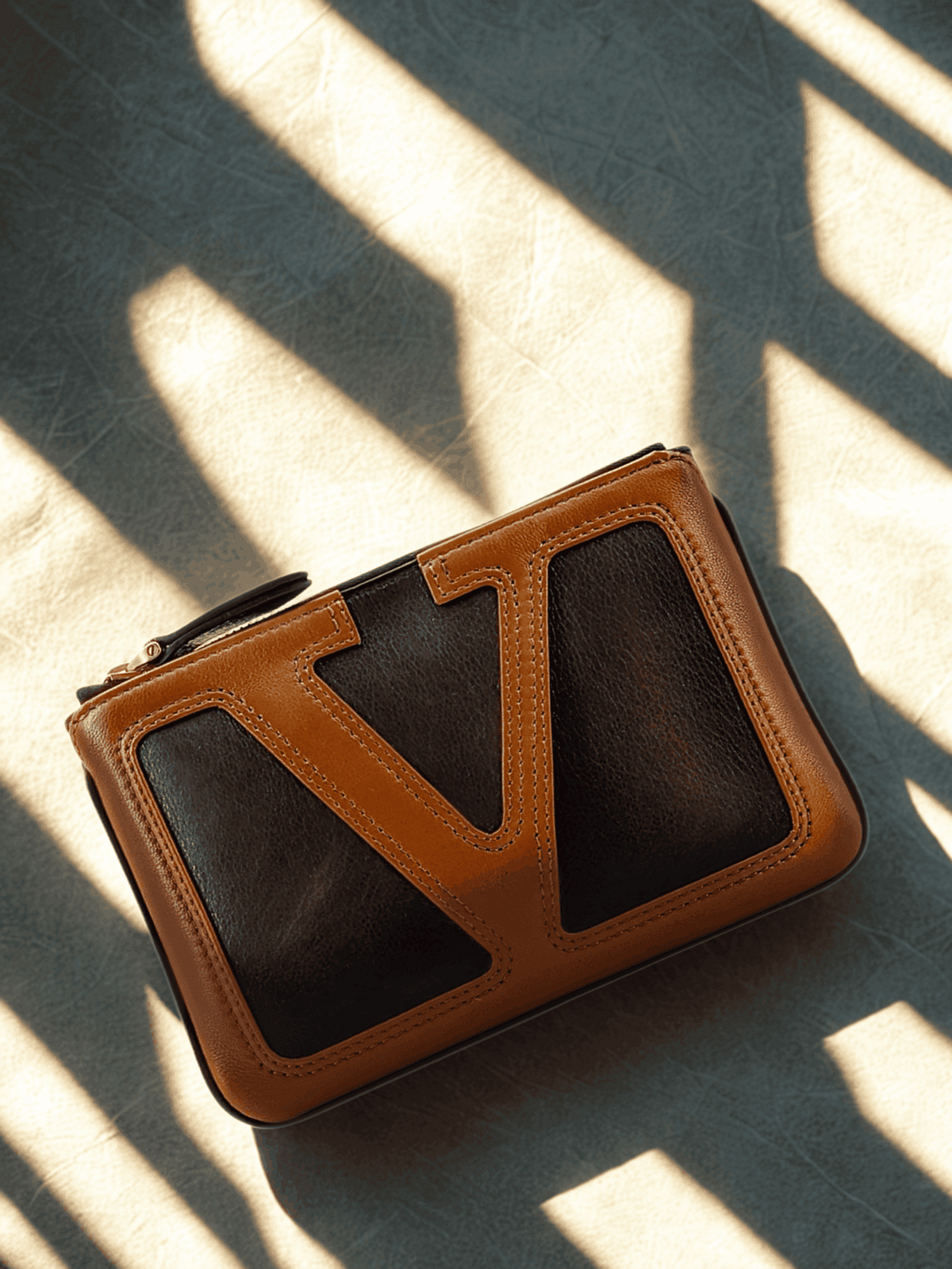 Valentino Garavani men’s leather crossbody bag in tan and black, featured on THE WISHLINE Men’s Collection — highlighting modern Italian design, bold detailing, and refined everyday sophistication.