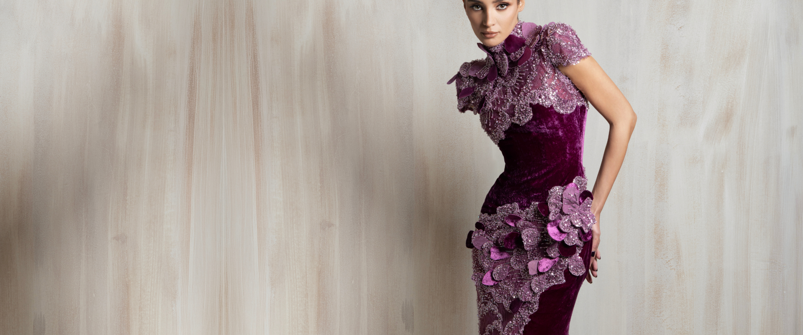 Close-up banner image of a model wearing a luxurious high-neck Ziad Nakad couture gown in deep purple velvet, intricately detailed with shimmering lilac sequins and 3D floral embellishments.